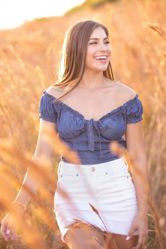 senior girl wearing an off the shoulder blue top and white mini skirt for her senior pictures