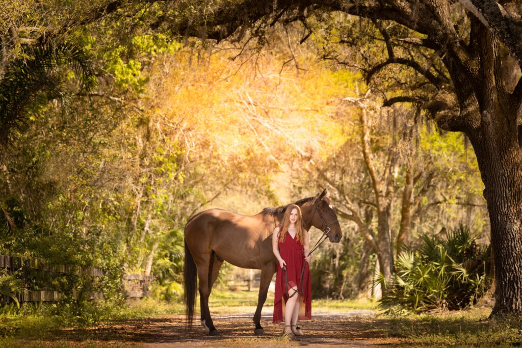 Spring Senior Picture Outfits: red head high school girl wearing timeless burgundy dress with her horse