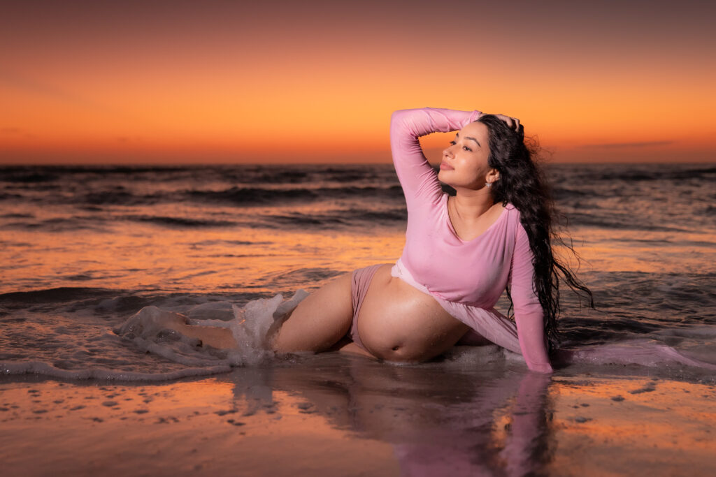 Pregnant woman reclining on Sand Key Beach at sunset