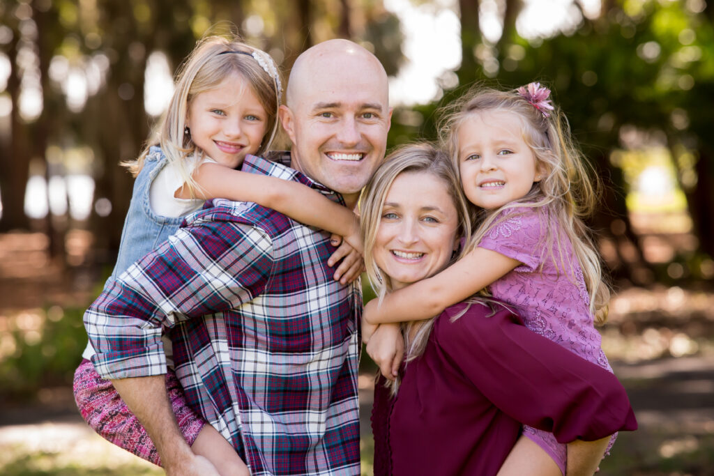 Family of 4 pose in coordinated outifts in Riverview park for Christmas family photoshoot