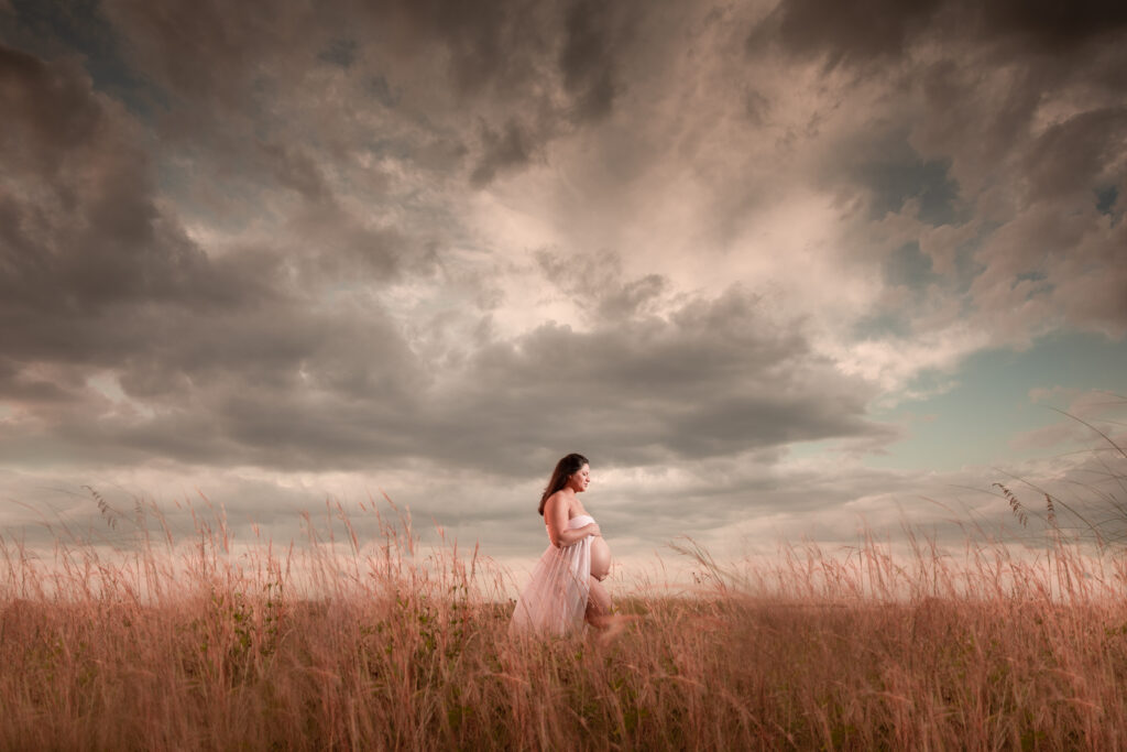 Pregnant woman wearing a white dress in a field during her Sand Key Park photo shoot 