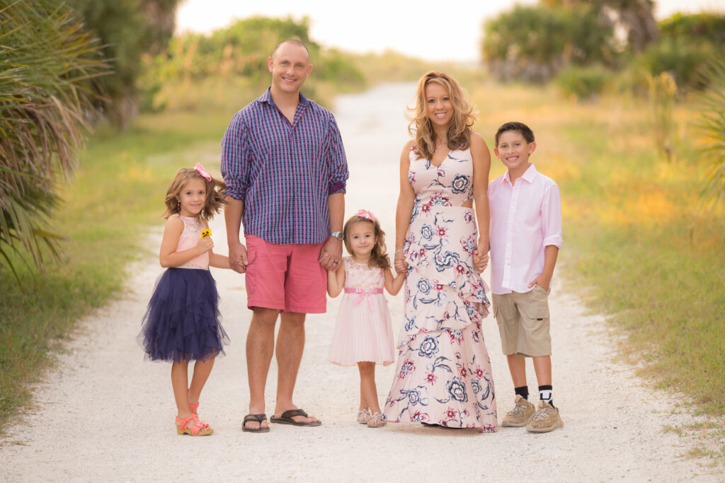 Family stands in sandy path at Sand Key Beach in Clearwater wearing pinks and blues
