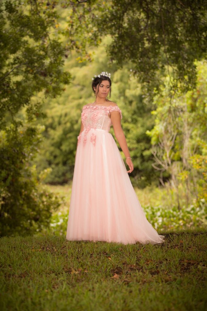 16-year-old Sophia wearing a lace pink dress in a forest for a "fairytale" sweet 16 photoshoot idea