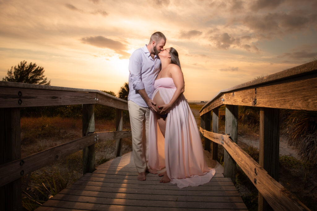 man and woman posing for a maternity shoot on the beach