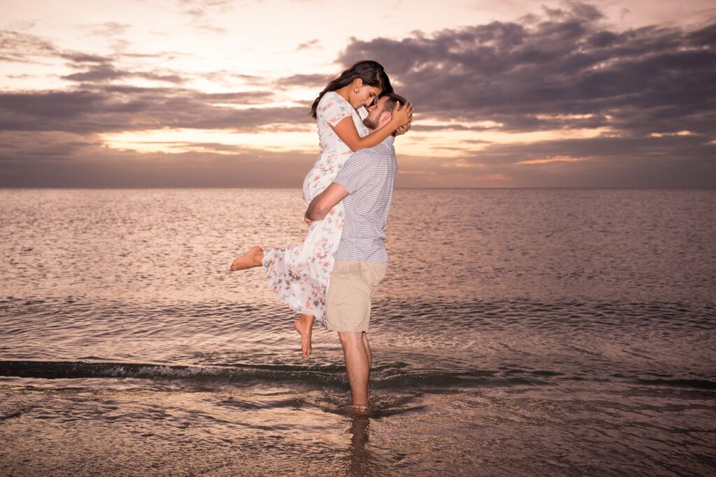couple on the beach at sunset - man holding woman up - ideas for celebrating mothers day