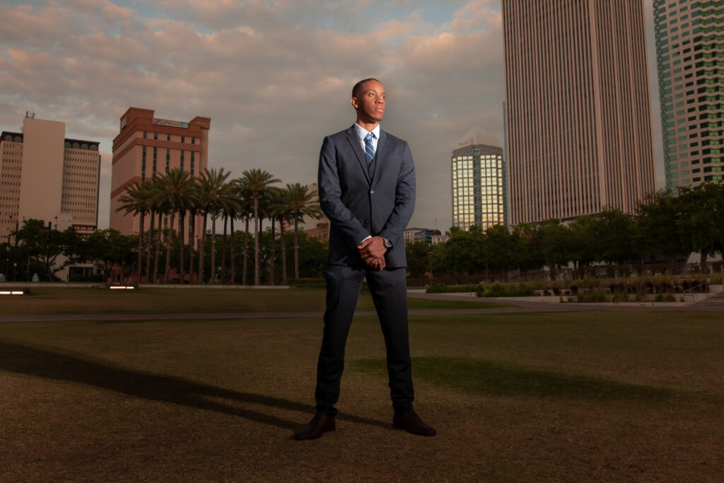 man in nice suit in front of Tampa skyline for senior portraits