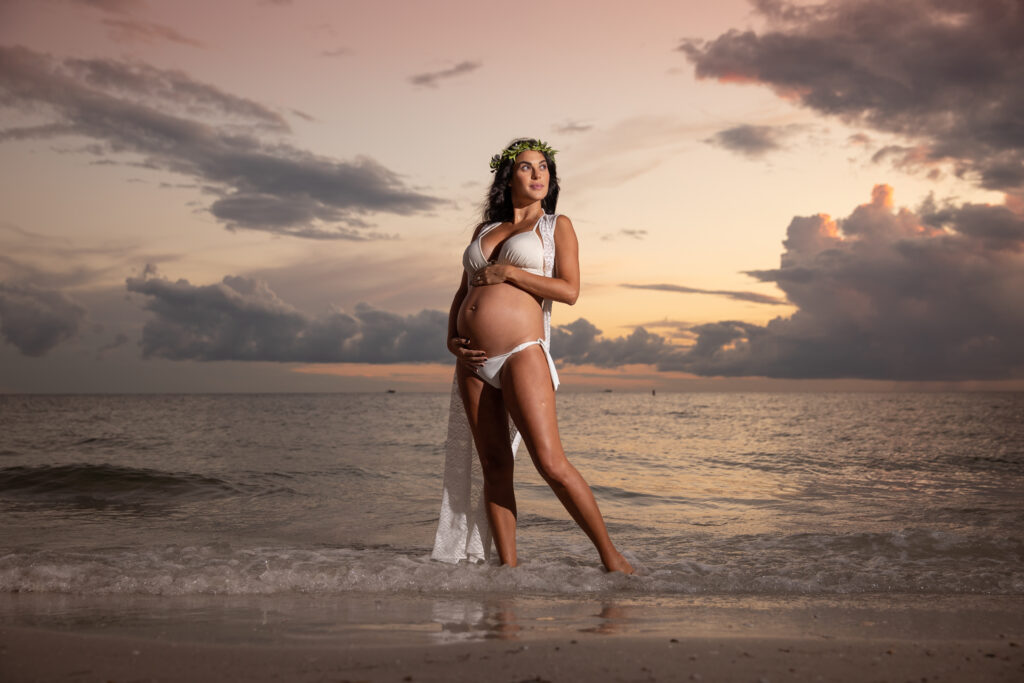 Maternity photo of woman standing in water with white bikini