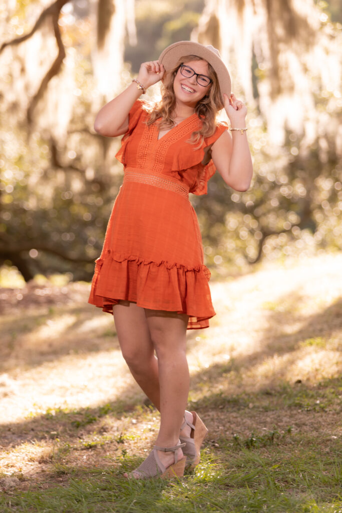blonde girl in orange dress posing for senior portrait in Phillippe Park near Tampa