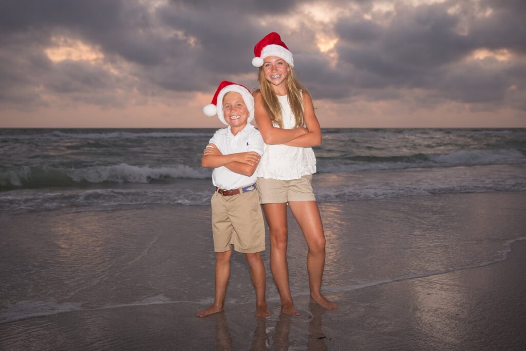 siblings wearing Santa hats on the Tampa beach for Christmas photoshoot
