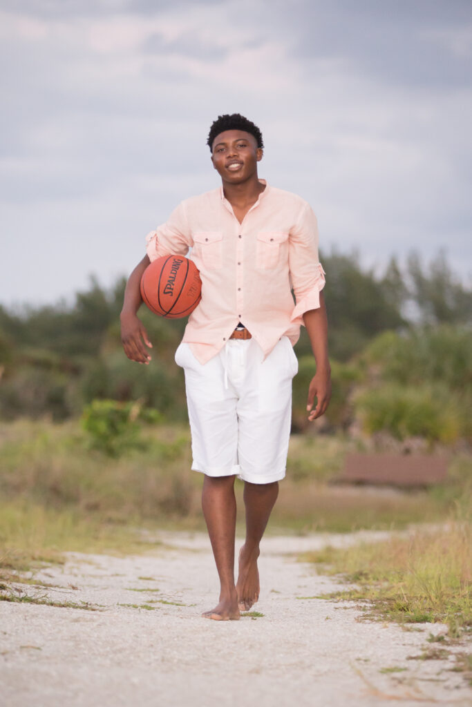 senior photoshoot outfit for guys with props - guy  wearing a light orange shirt to pair with the dark orange basketball. 