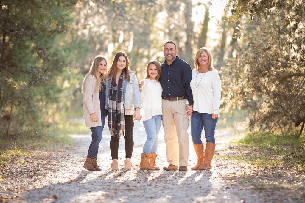 Family of 5 dresses in coordinated neutral outfits for Christmas photoshoot in Jay B. Starkey Park in New Port Richey